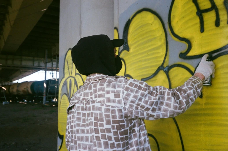 a man in a jacket writing on a yellow and black wall