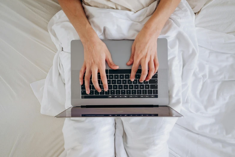 a person in white pajamas holding their laptop