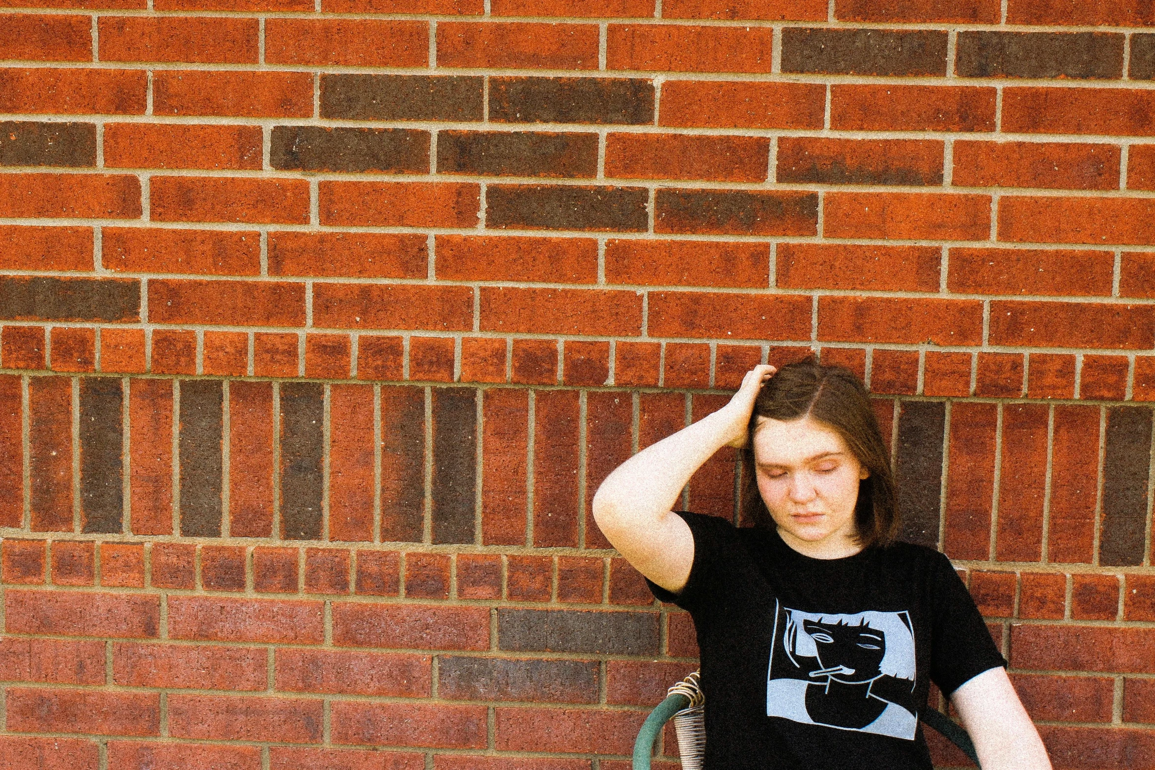  leaning against brick wall and holding tennis racket