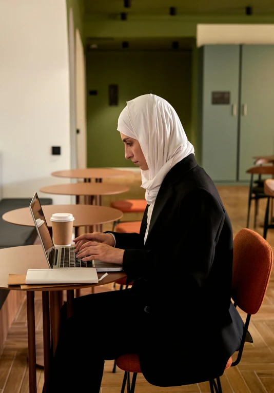 the person wearing hijab is using a laptop at a table