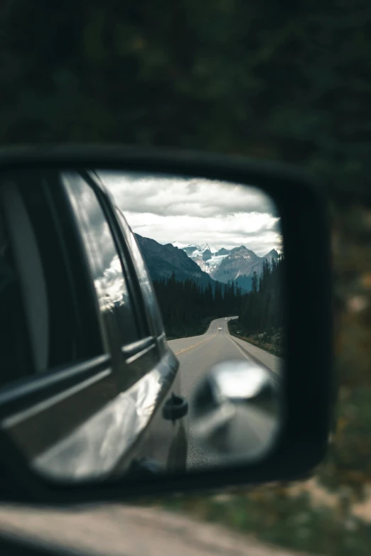 a car's side view mirror reflects the mountain view