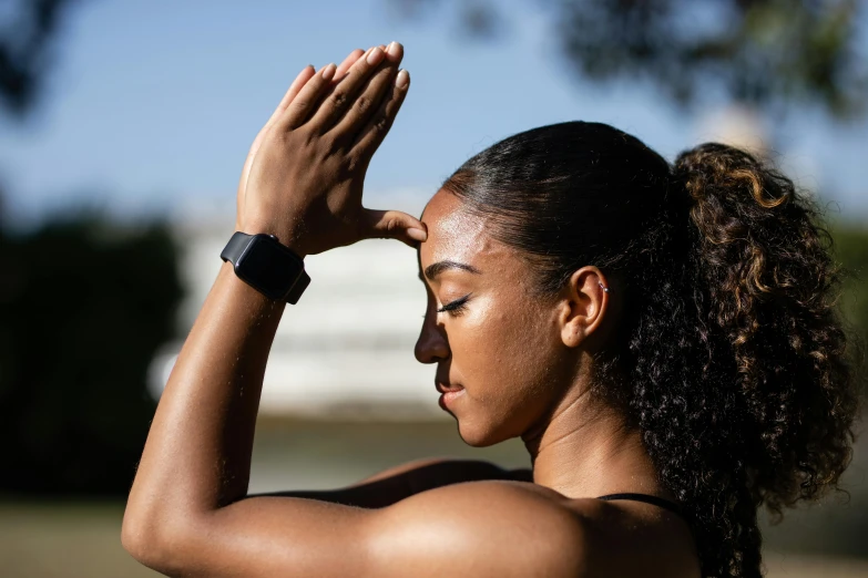 a young woman holds her hand on her head as she looks down at soing