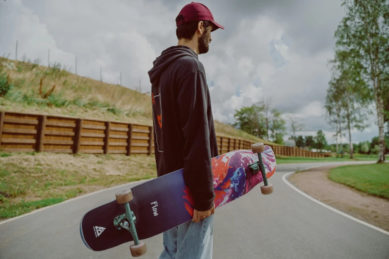 a man standing next to a road holding a skateboard