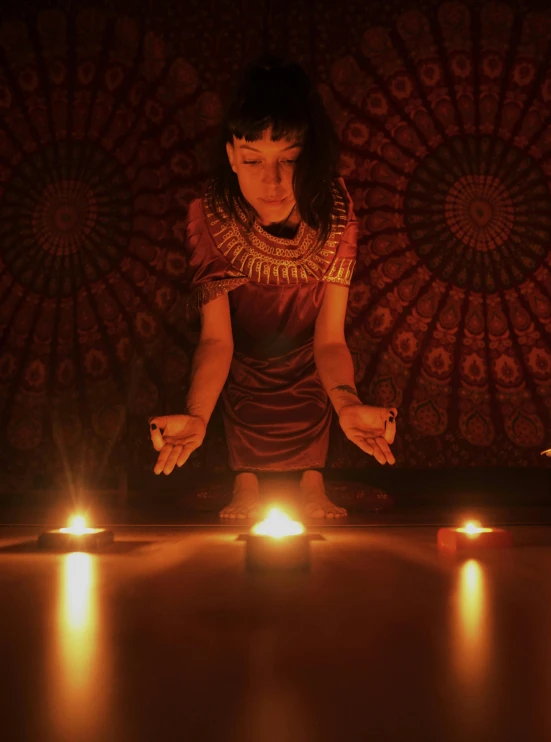 woman on the floor surrounded by candles holding her hands out