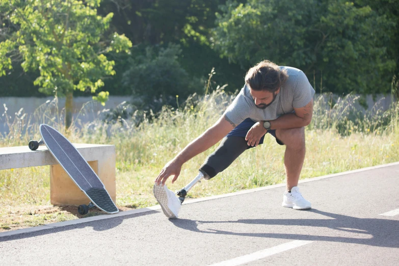 a skateboarder in a white shirt bent over while trying to break up with his board