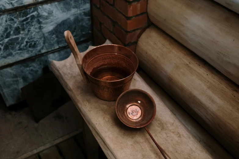 a bowl, a candle and spoon sit on the table in a room with brick pillars