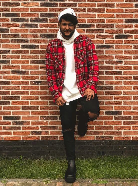 a man standing on a sidewalk in front of a brick wall