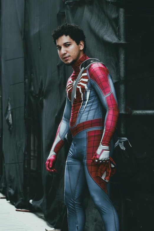 the man dressed in the spider - man costume stands in front of a wall