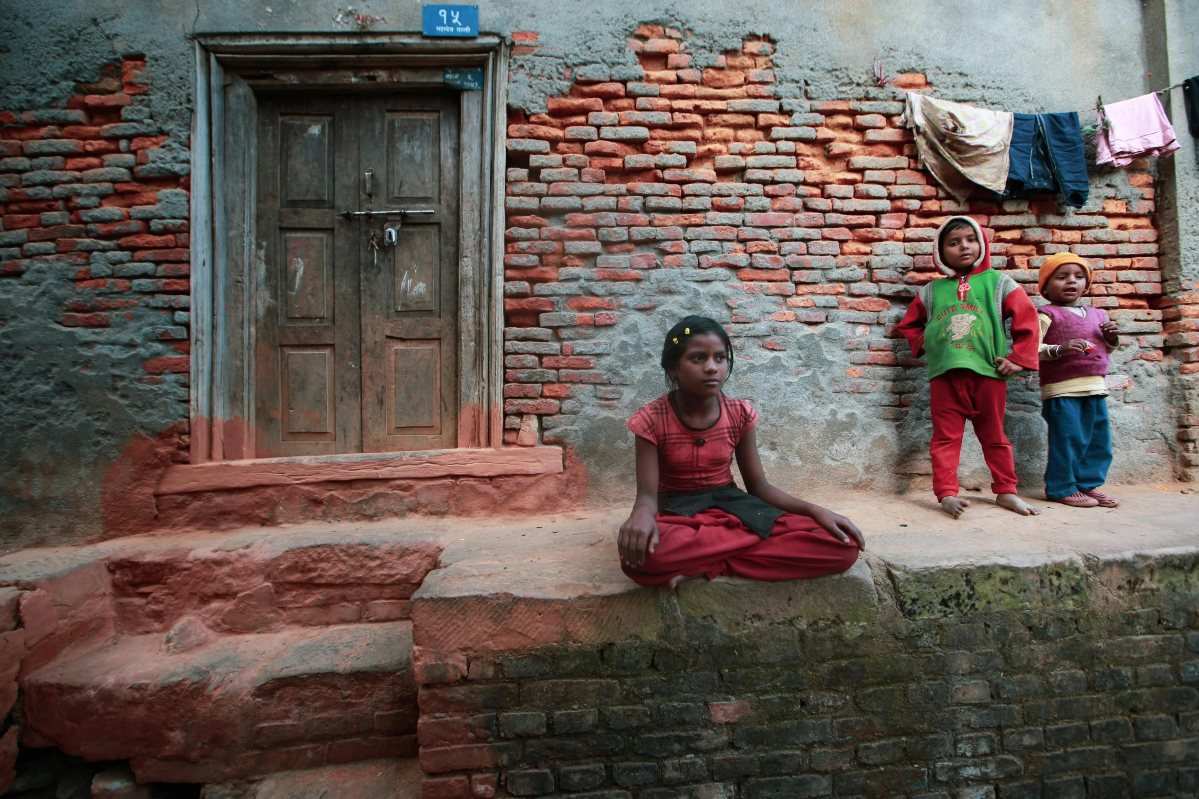 a group of young children standing in front of a brick wall