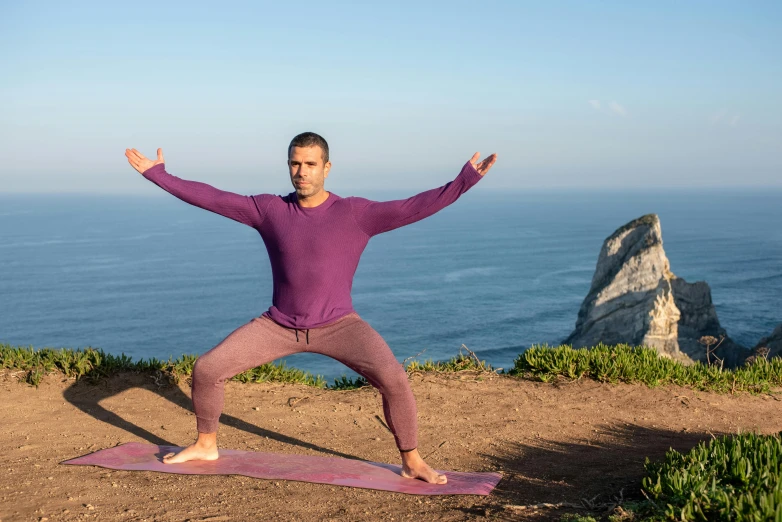 a man in yoga poses on the top of a mountain