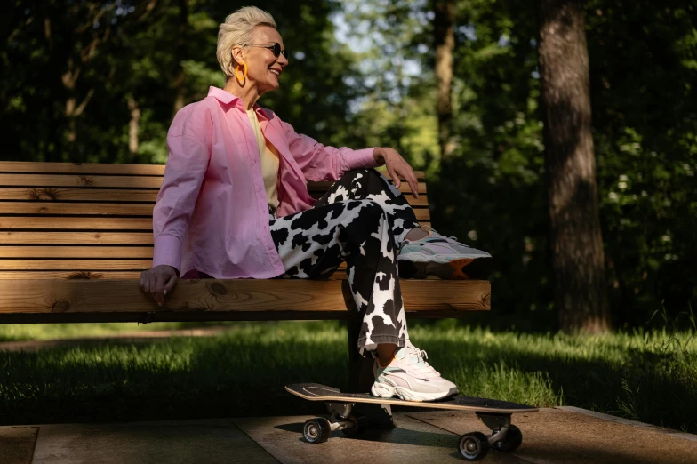 a smiling older woman sitting on a bench next to her skateboard