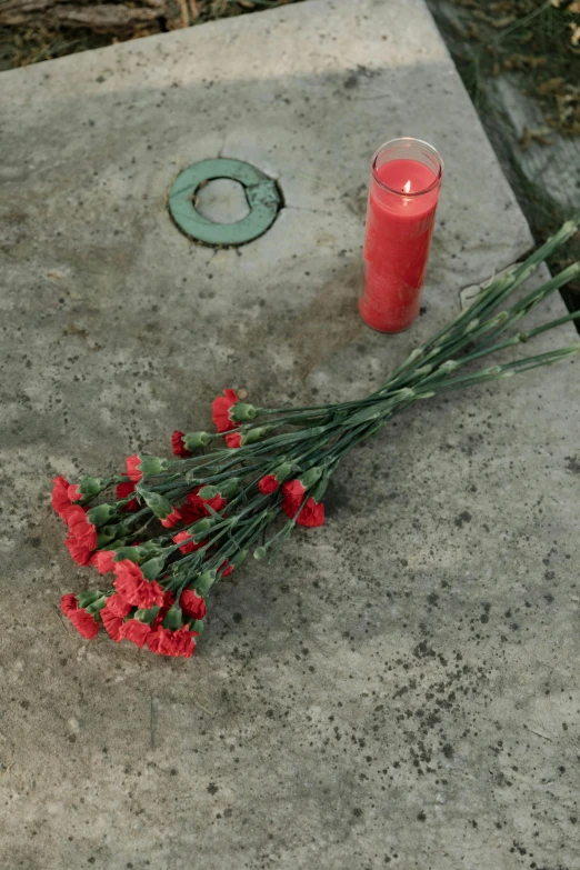 some red flowers and candles on a cement surface