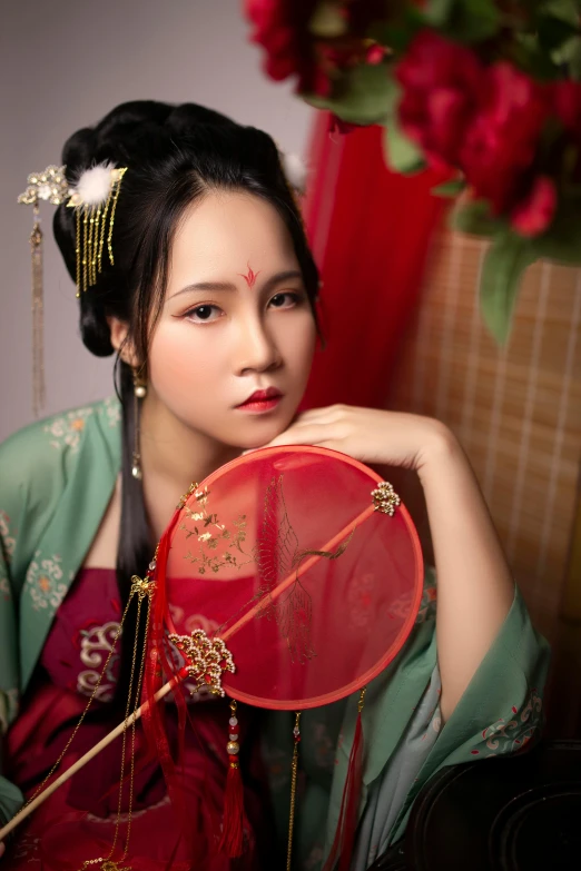 a woman with oriental hair holds a fan and looks at the camera