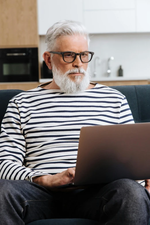 an old man using a laptop computer on a couch