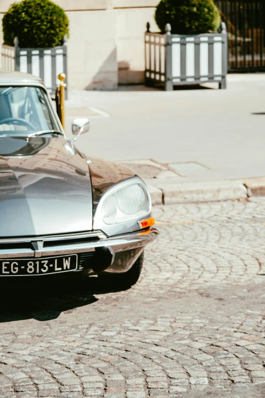 an old car parked outside on a cobblestone surface