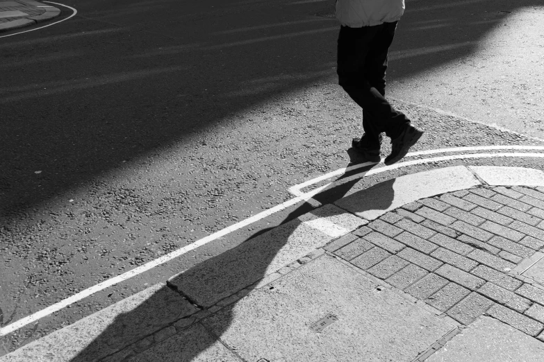 the man is walking down the side of the road while talking on the cell phone