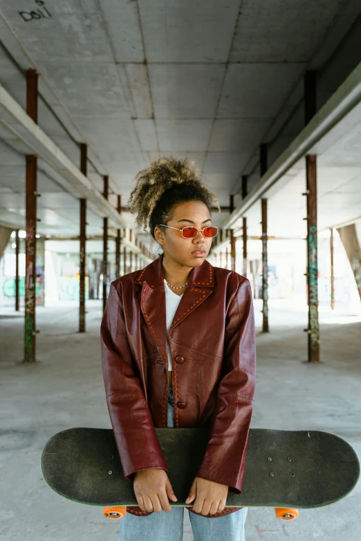 a young woman poses on a skateboard in a parking garage