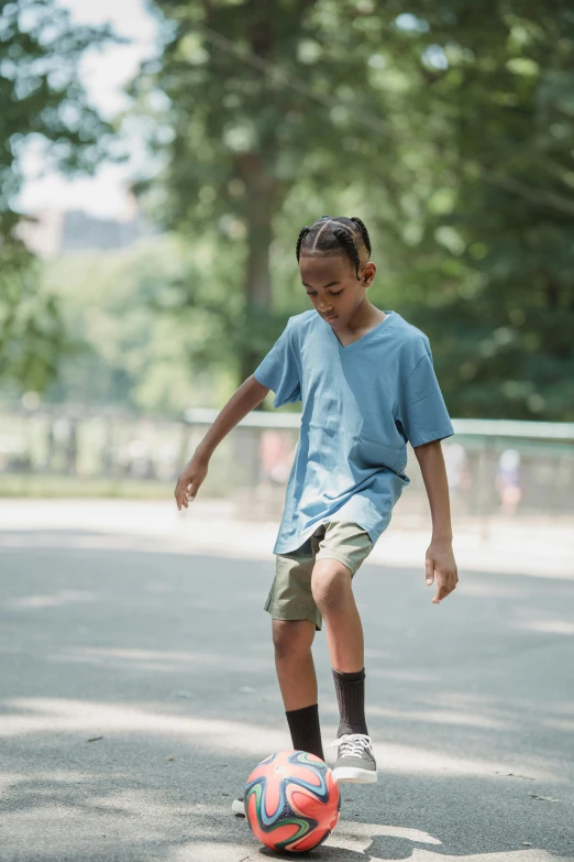 boy playing soccer on a playground field in a park