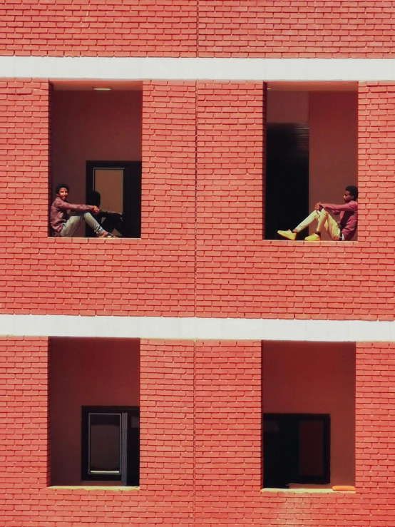 two people sit in windows and look out from their balconies