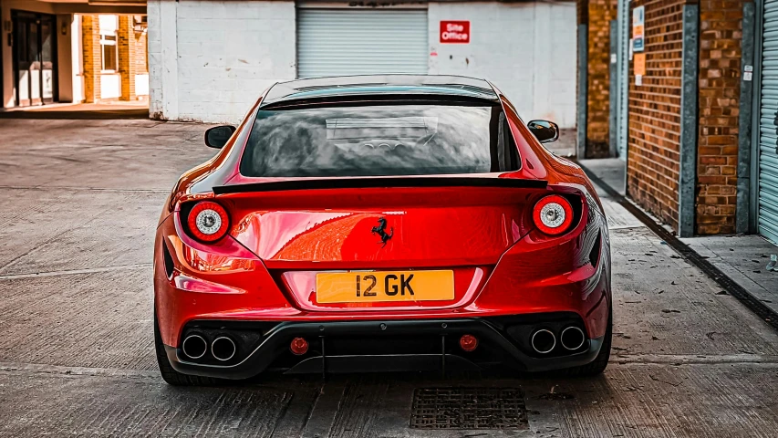 the back end of a red sports car parked in a parking lot