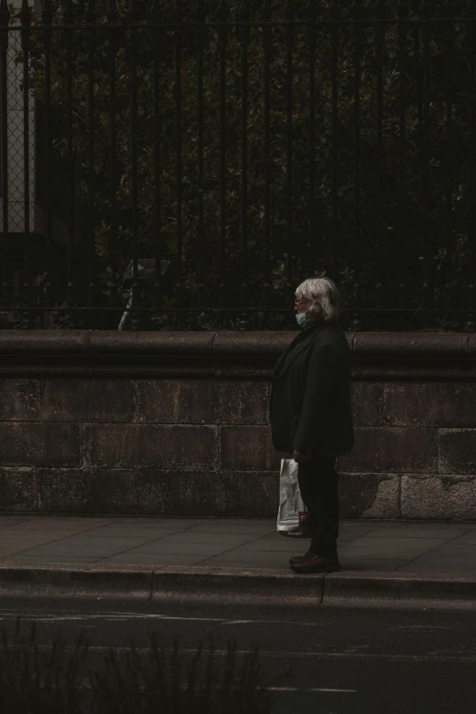 a person walking down a sidewalk near a fence