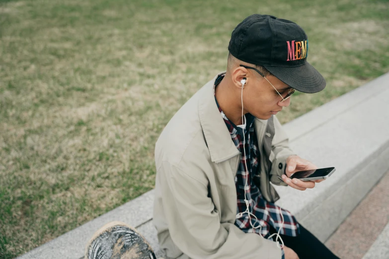 a boy in plaid shirt and earphones using a cell phone