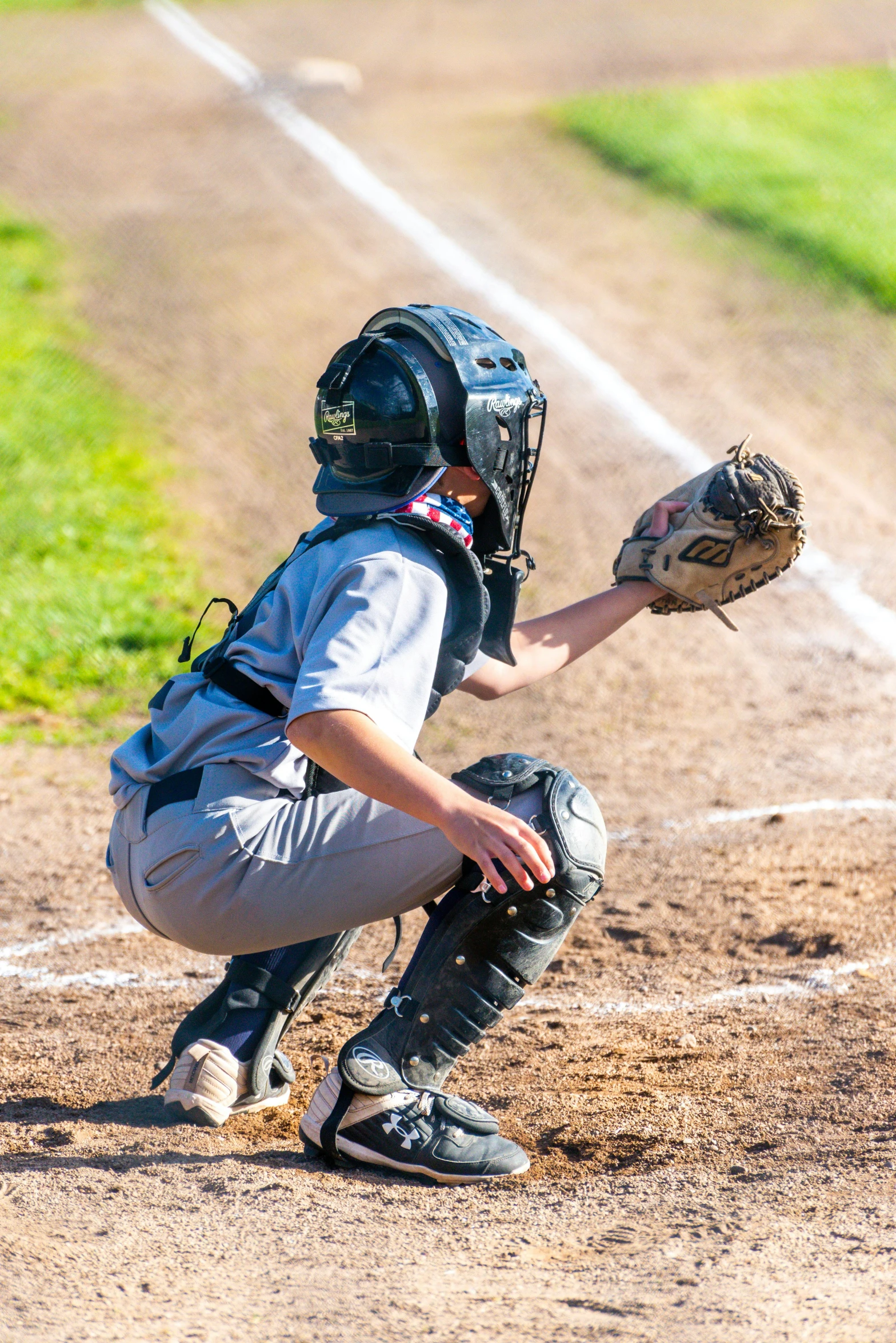 a little league batter kneeling down before getting ready to hit a ball