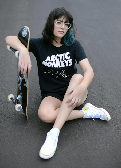 a woman sitting on the street with a skateboard