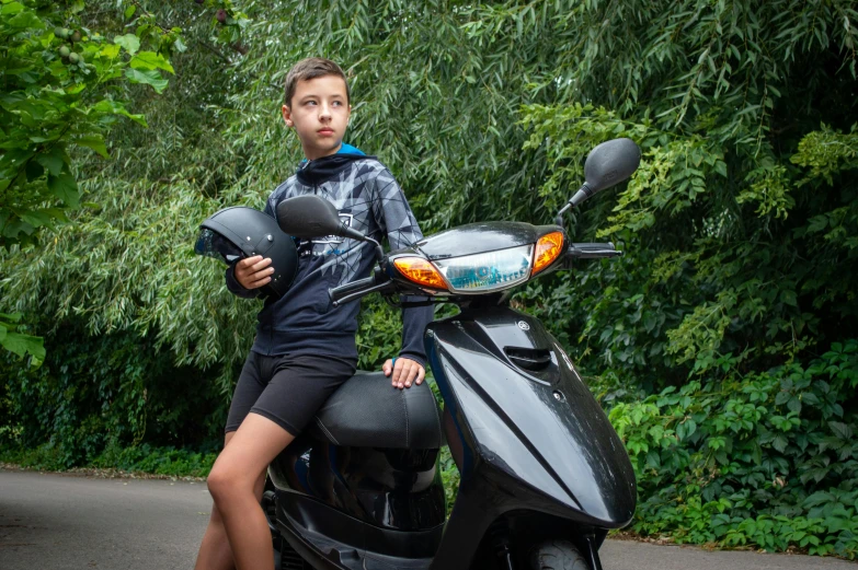 a boy that is sitting on top of a motor scooter