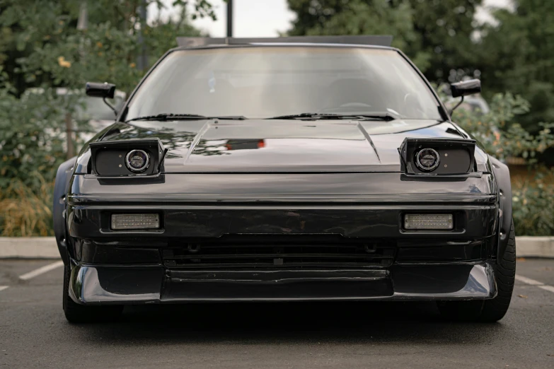 a car with lights on sits in the parking lot