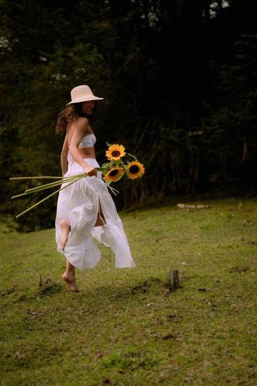 a woman in a white dress and hat holds flowers