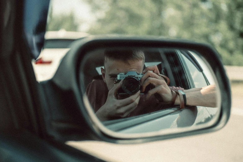 a man takes a pograph of himself in the rear view mirror