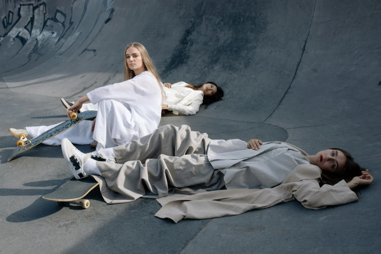 two people sitting on the ground in front of a skate park