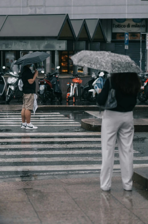 a man holding an umbrella and cross a street in the rain