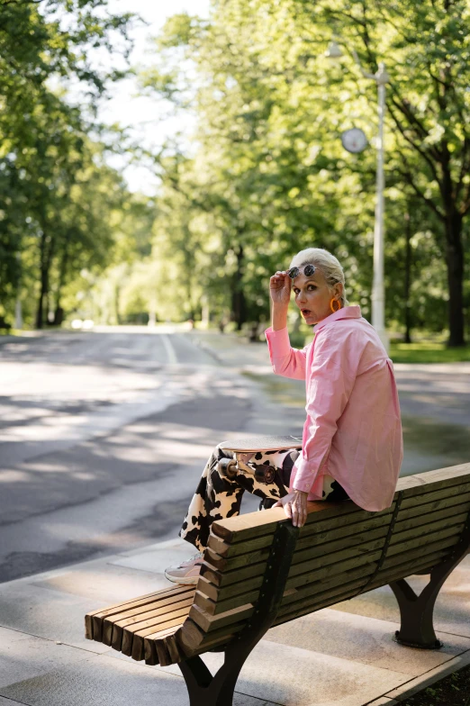 a woman sits on a bench in a park