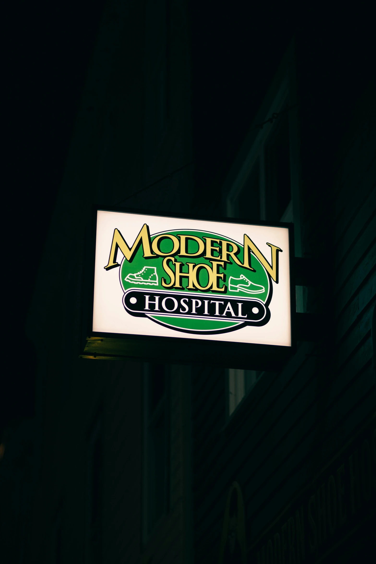 a neon sign hangs from the side of a dark building