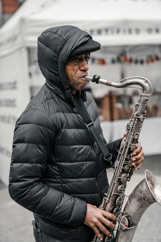 a man in black jacket playing on a saxophone