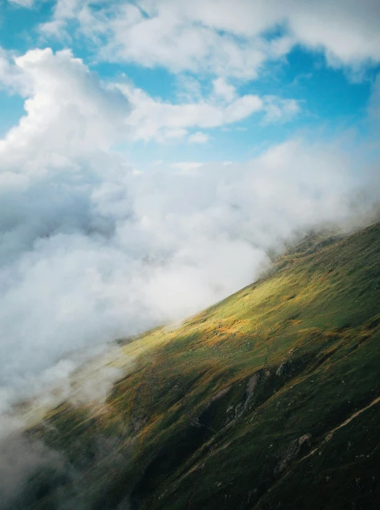 the clouds are blowing on the top of the mountain