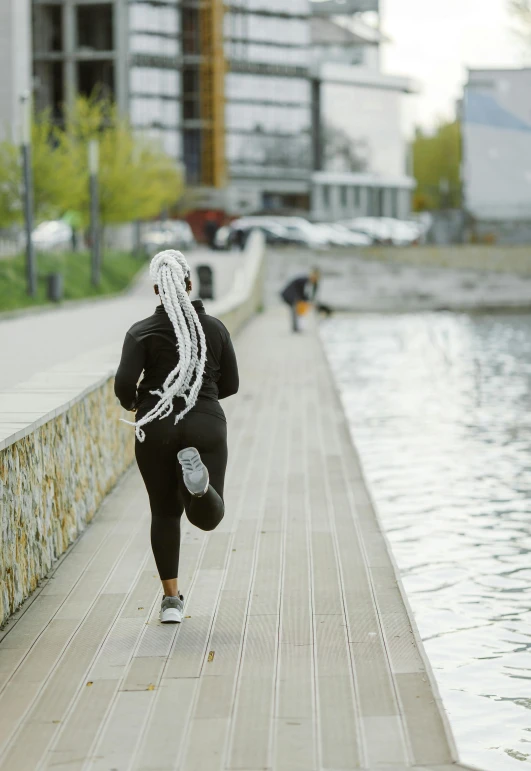 a woman running on the waterfront in front of some water