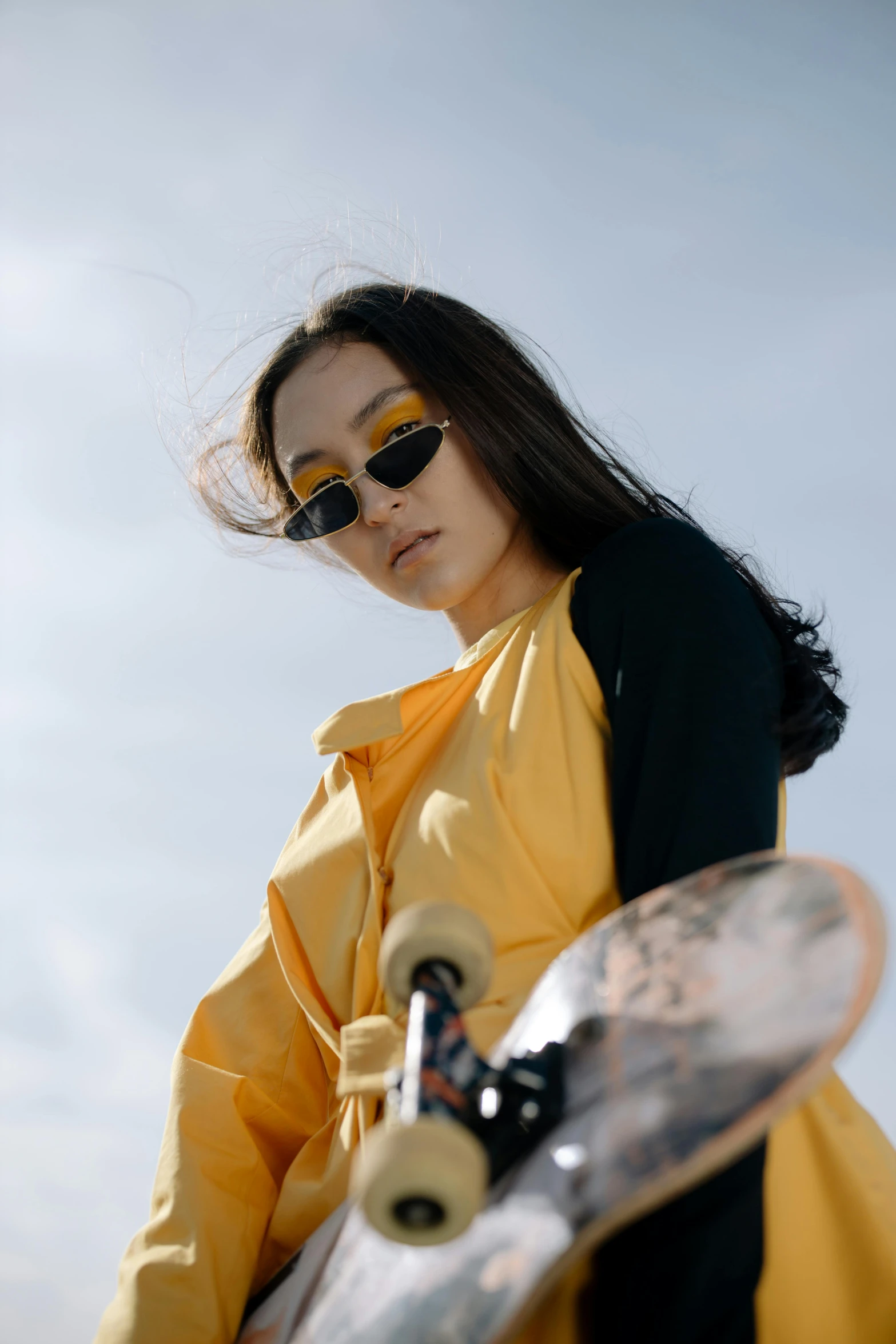 a girl wearing shades is holding her skateboard