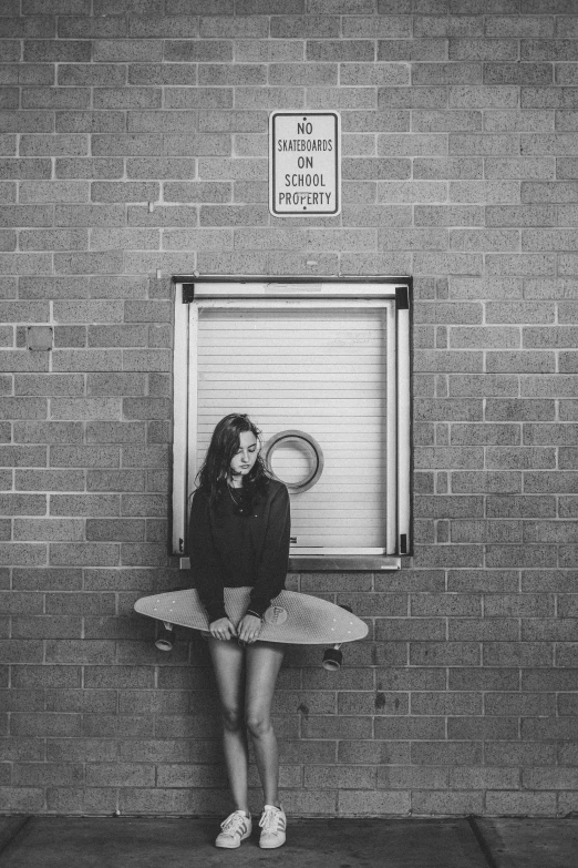 the woman is sitting on her skateboard in front of a locker