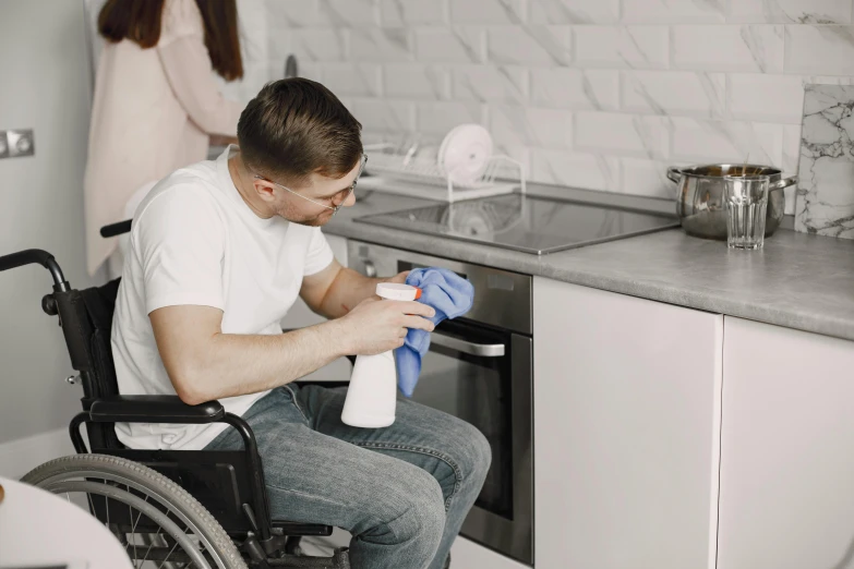 a man in a wheel chair is cleaning an oven