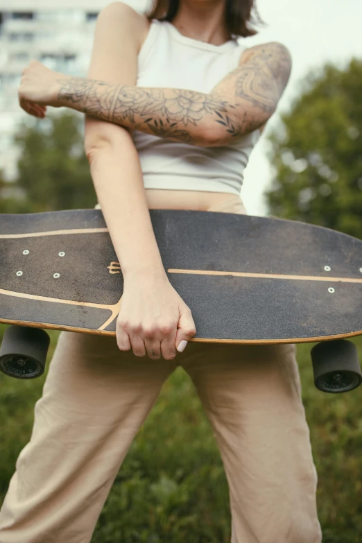 a young person holding a skateboard under their arms