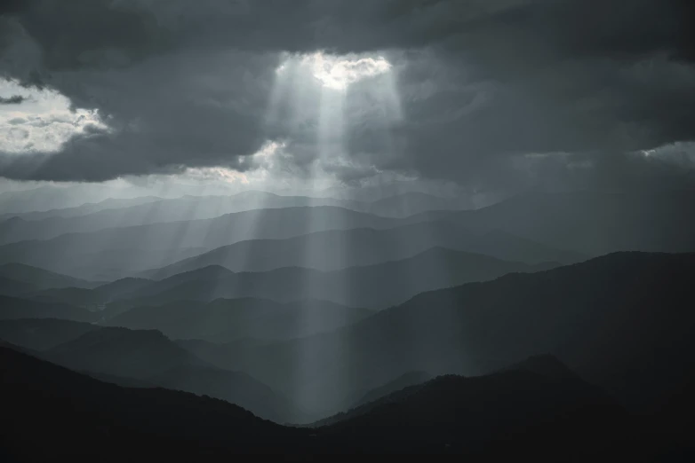 a dark cloudy sky with light beams coming through