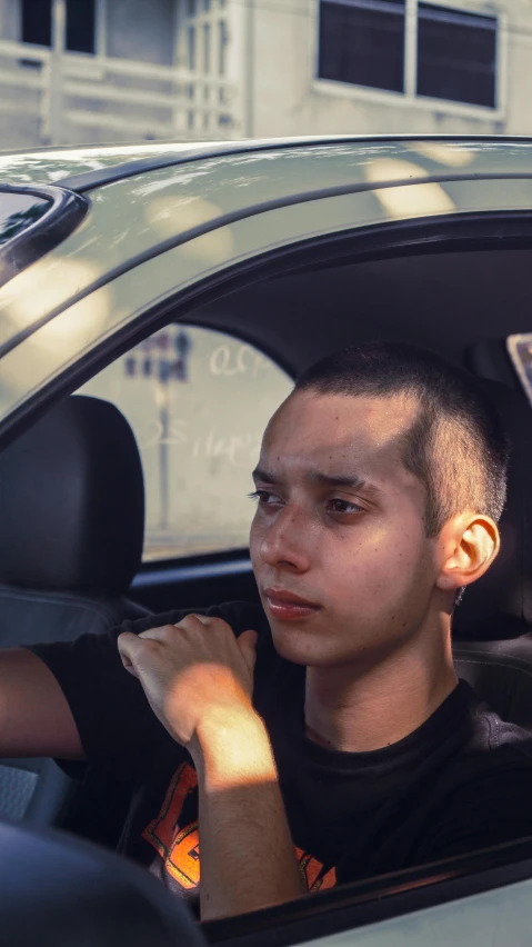 a boy with shaved head sitting inside of a car