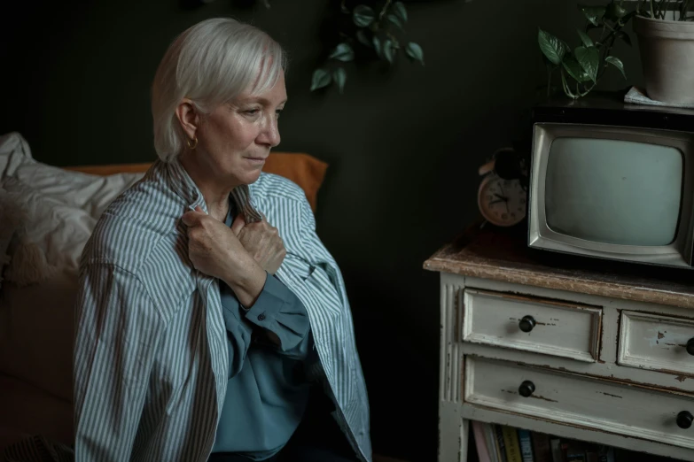 a woman holds her hand in her pockets, standing next to a tv