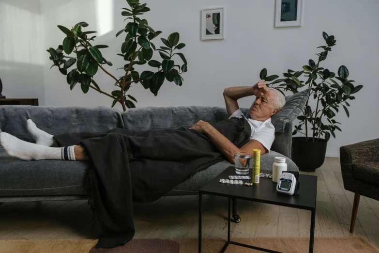 a man lays on a couch with two cups of beer