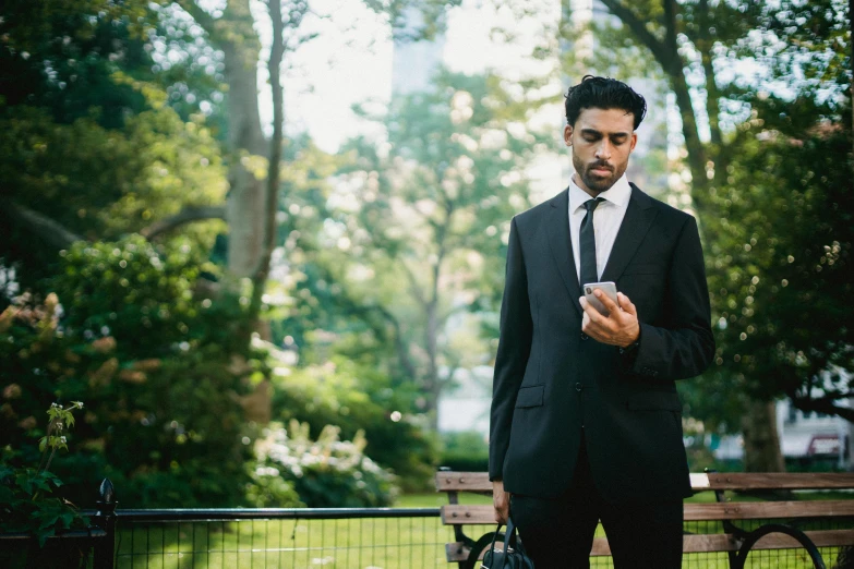 man in a black suit holding a cell phone