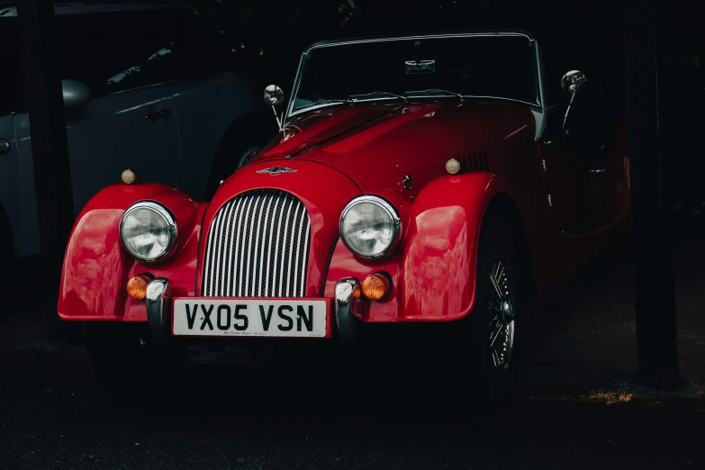 an old red car with chrome hood parked next to another