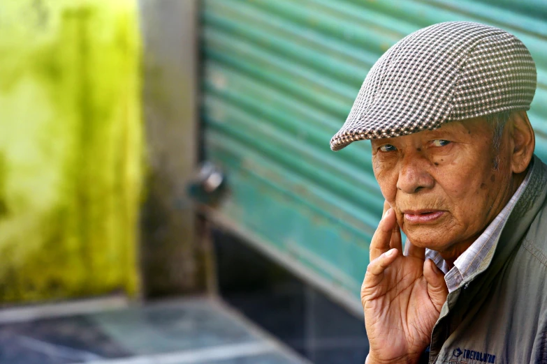 an elderly man talking on a phone with his hand to his face